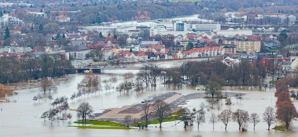 Hochwasser durch Starkregen an der Weser. Überflutete Felder und Häuser. Hilfe bei Wasserschaden durch Regen